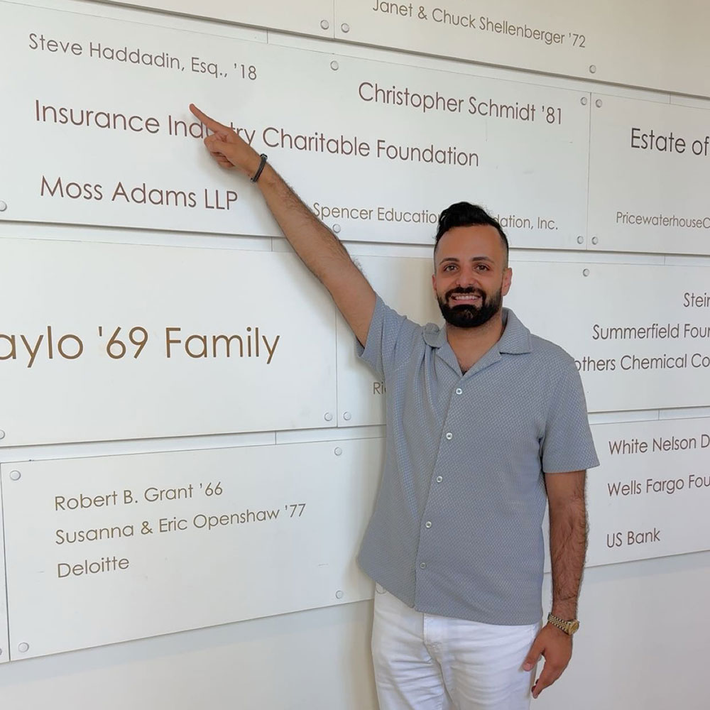 Steve Haddadin in 2025 pointing at his wall dedication.