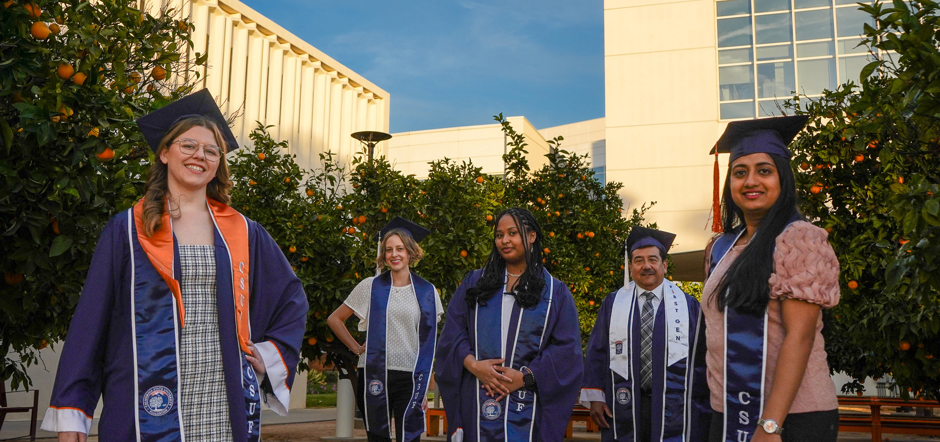 Graduates taking a group picture, wearing regalia.